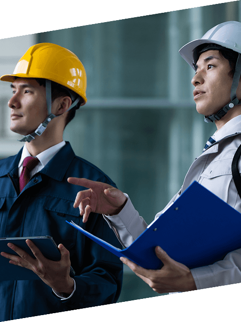 ヘルメットを着用した作業員がタブレットを見ながら現場の確認を行っている様子